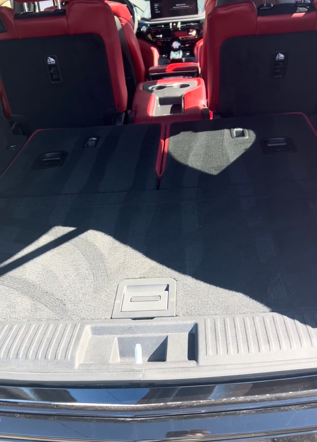 Black carpeted vehicle cargo area with red leather seats folded flat for maximum storage space.