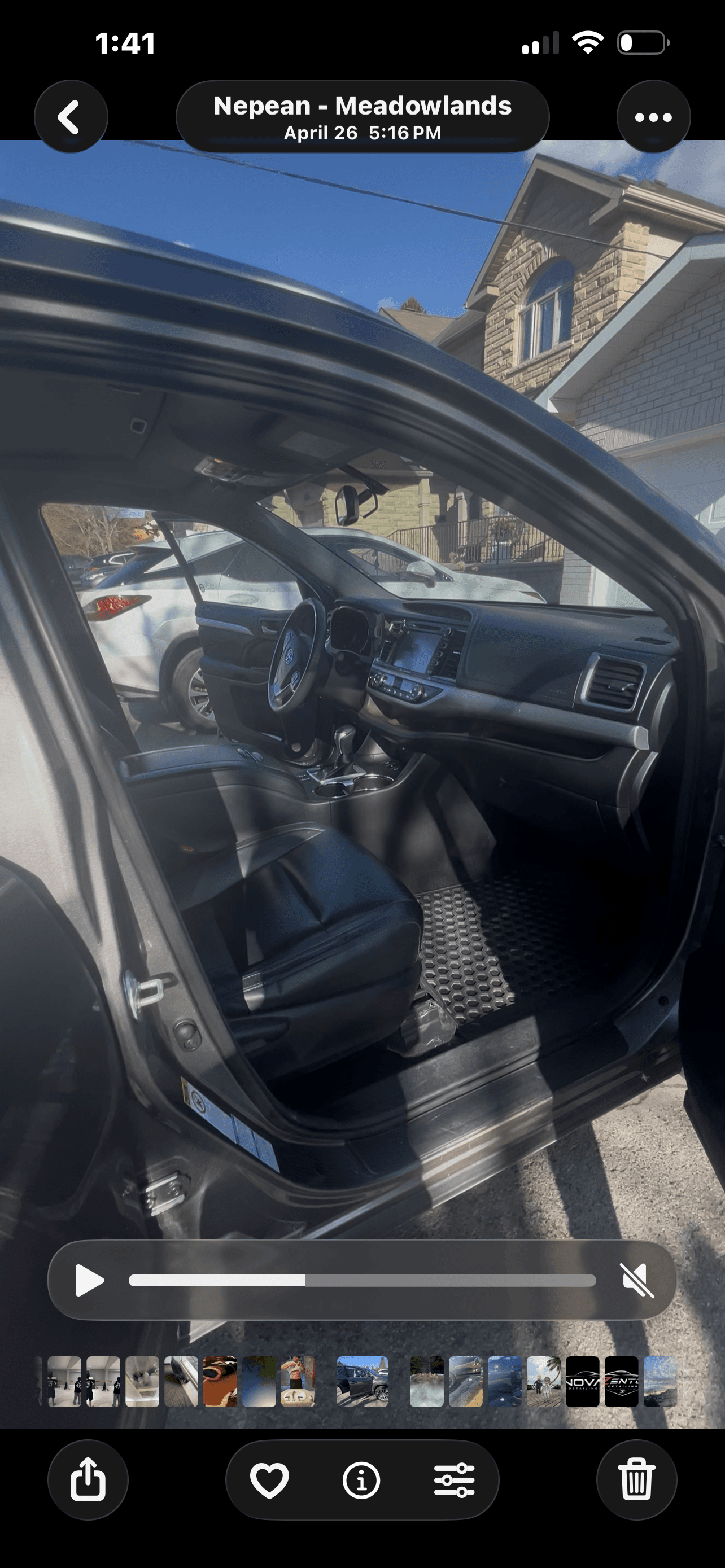 Toyota car interior with black leather seats and an open door in a sunny driveway.